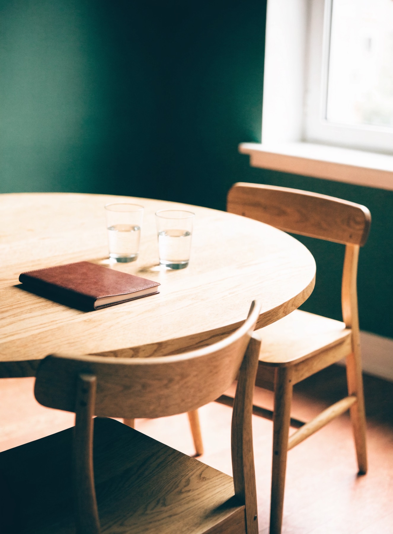 Een ronde tafel met twee stoelen in warm licht, niemand zit aan het hoofd